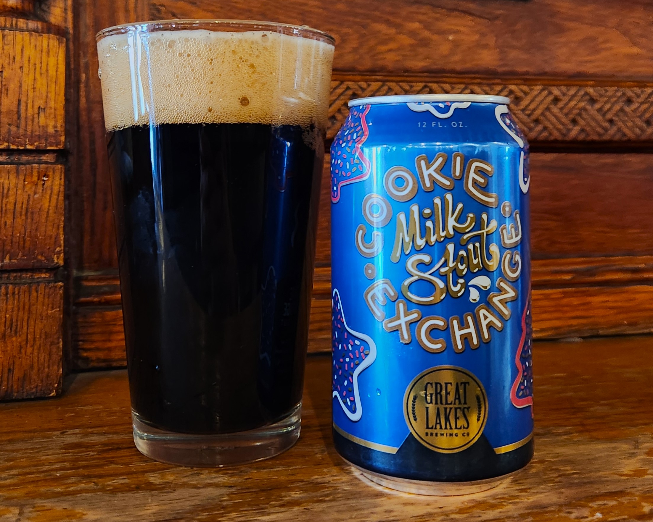 Can and pint of Cookie Exchange Milk Stout in front of a wooden background.