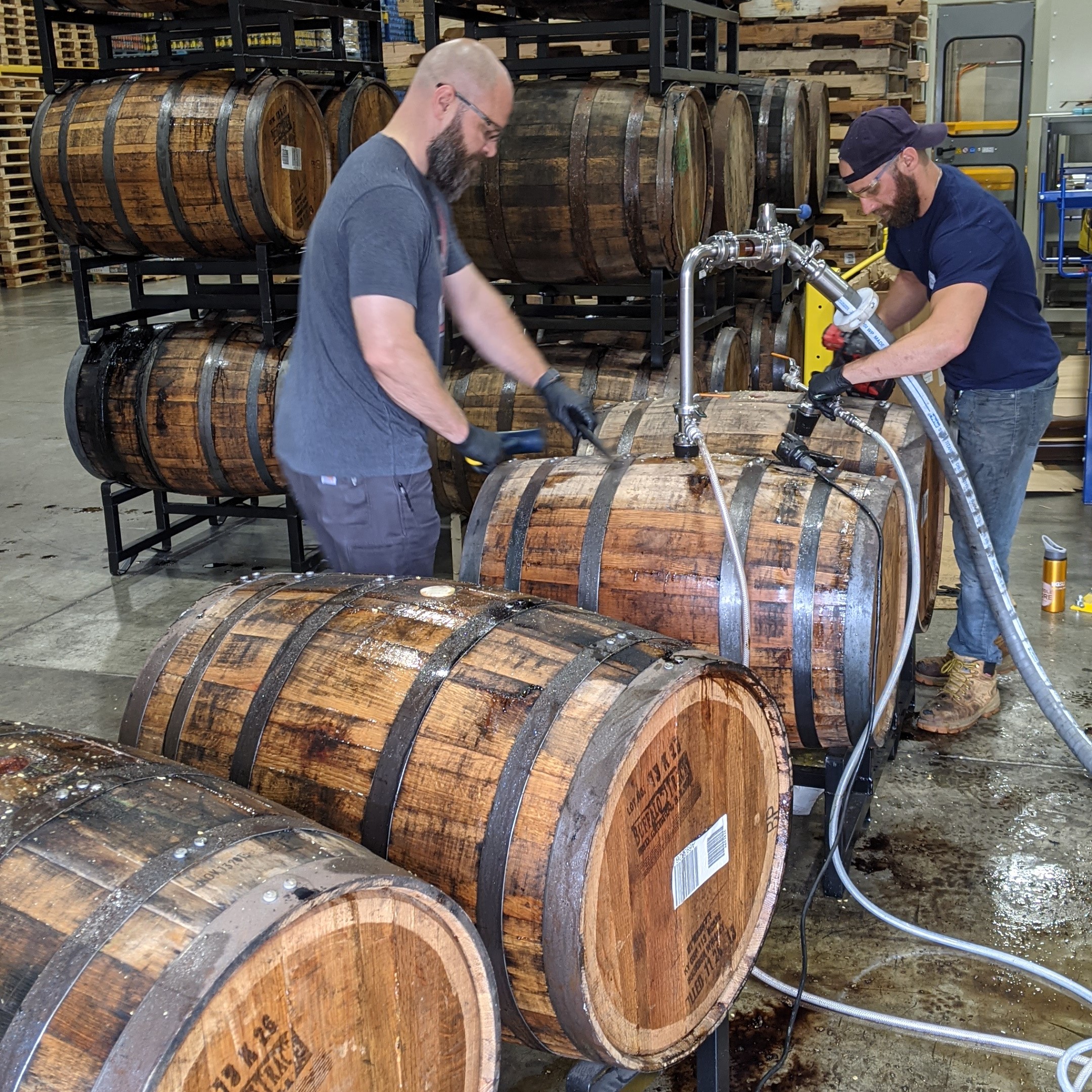 Barrel program director Justin Michalovic and Cellar Tech David Gerding transferring beer our of bourbon barrels.